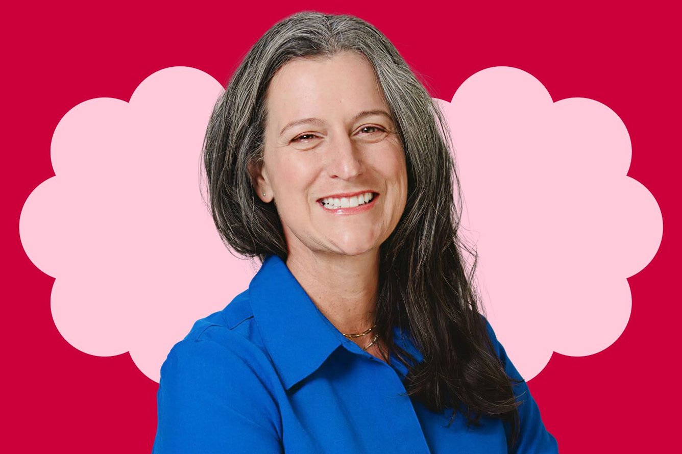 Headshot of Summer Weisberg, a white woman with long wavy salt and pepper hair, wearing a blue button down shirt and smiling widely at the camera.