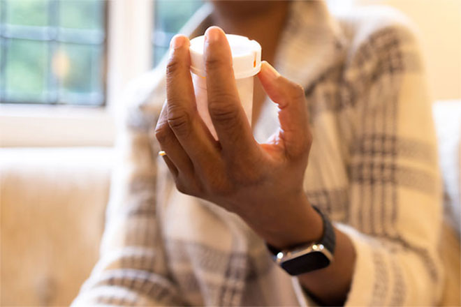 A hand holding a medicine bottle.