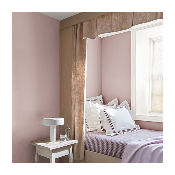 A pink painted bedroom features a built-in bed with purple linens and frilly pillows.