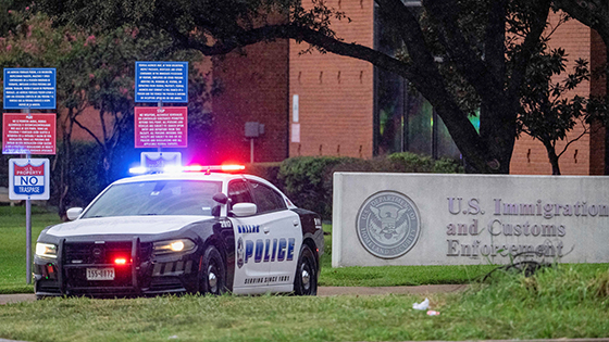 A police car in front of a U.S. Immigration sign
