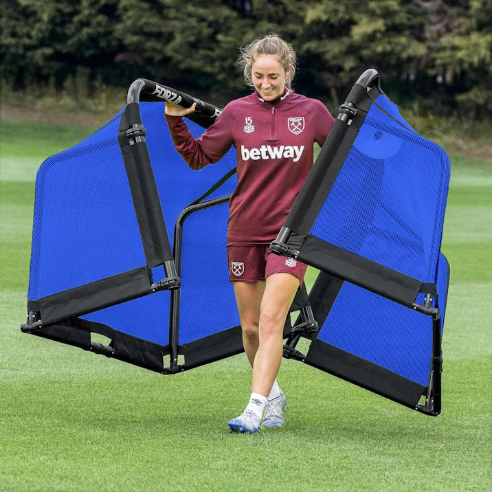 West Ham Womens player walking across an artificial pitch carrying two FORZA POD Goals in Blue.