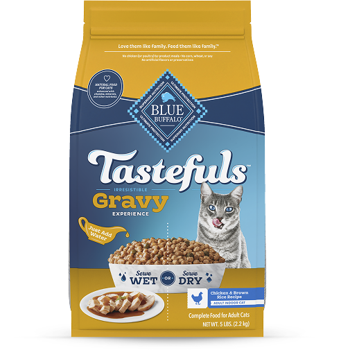 A bag of BLUE Tastefuls Gravy dry cat food is next to a bright yellow flower.