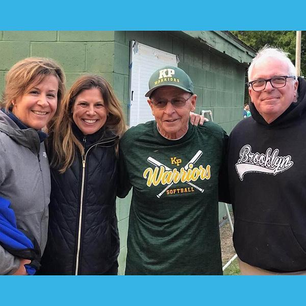 Assistant coach Bill Kelley (in cap) gets a good-luck visit from his Dana-Farber clinicians (left to right) Amy Joyce, Jen Brock, and Robert Soiffer before a high school softball playoff game.