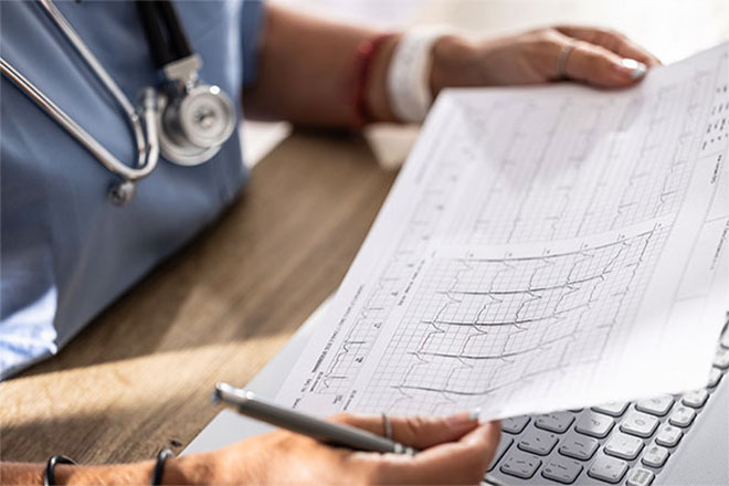A doctor looks at a chart of cardiac activity.