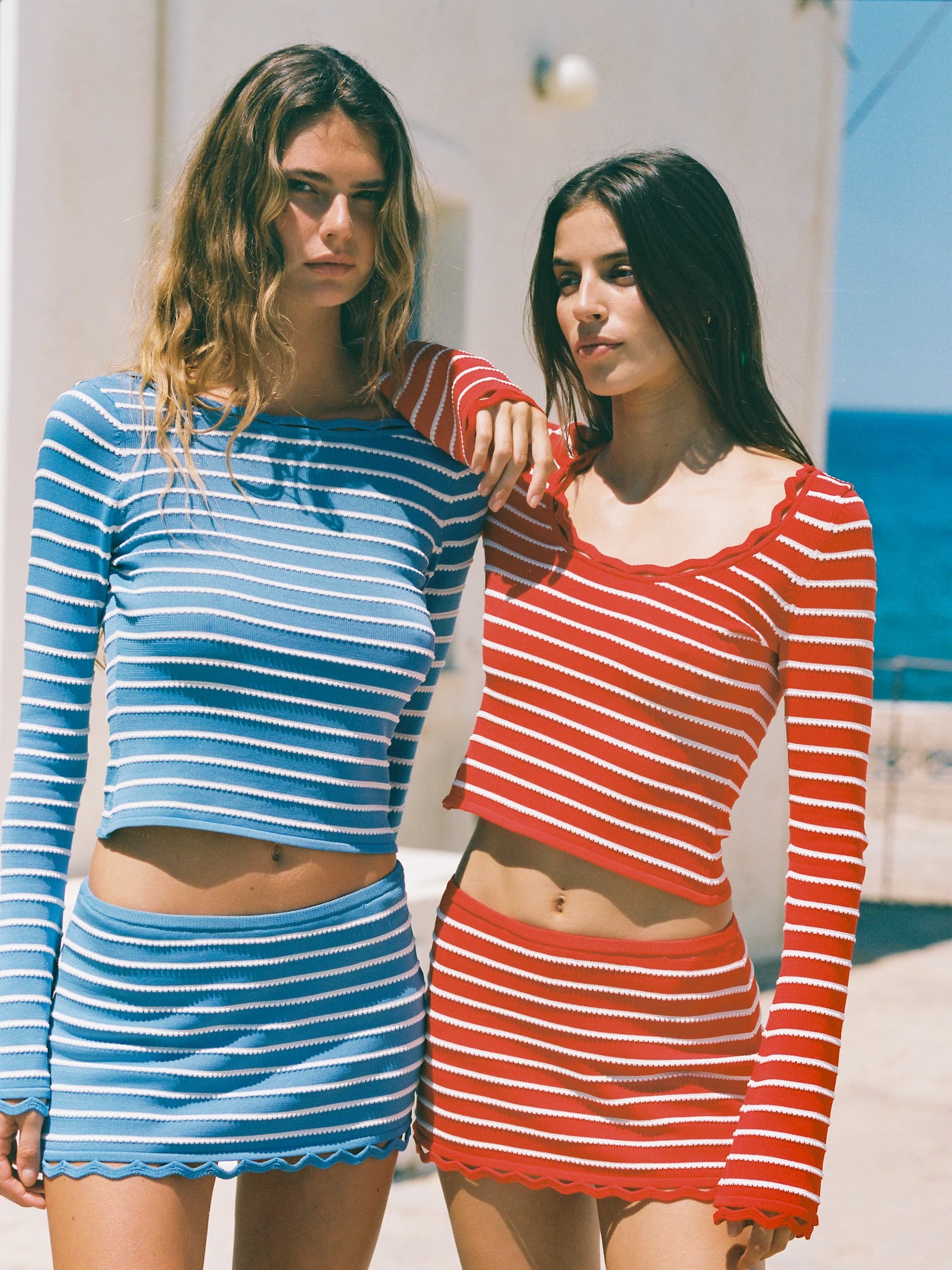 Woman wearing a blue and white striped top and skirt and woman wearing a red and white striped top and skirt