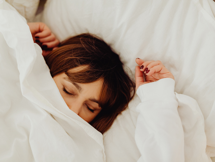 Lady sleeping under white bedsheets