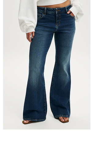 Model wearing white cropped sweater and dark blue wide-leg flare jeans with sandals