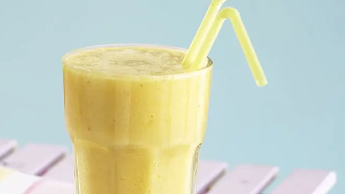 Mango frappe in a tall glass with a straw.