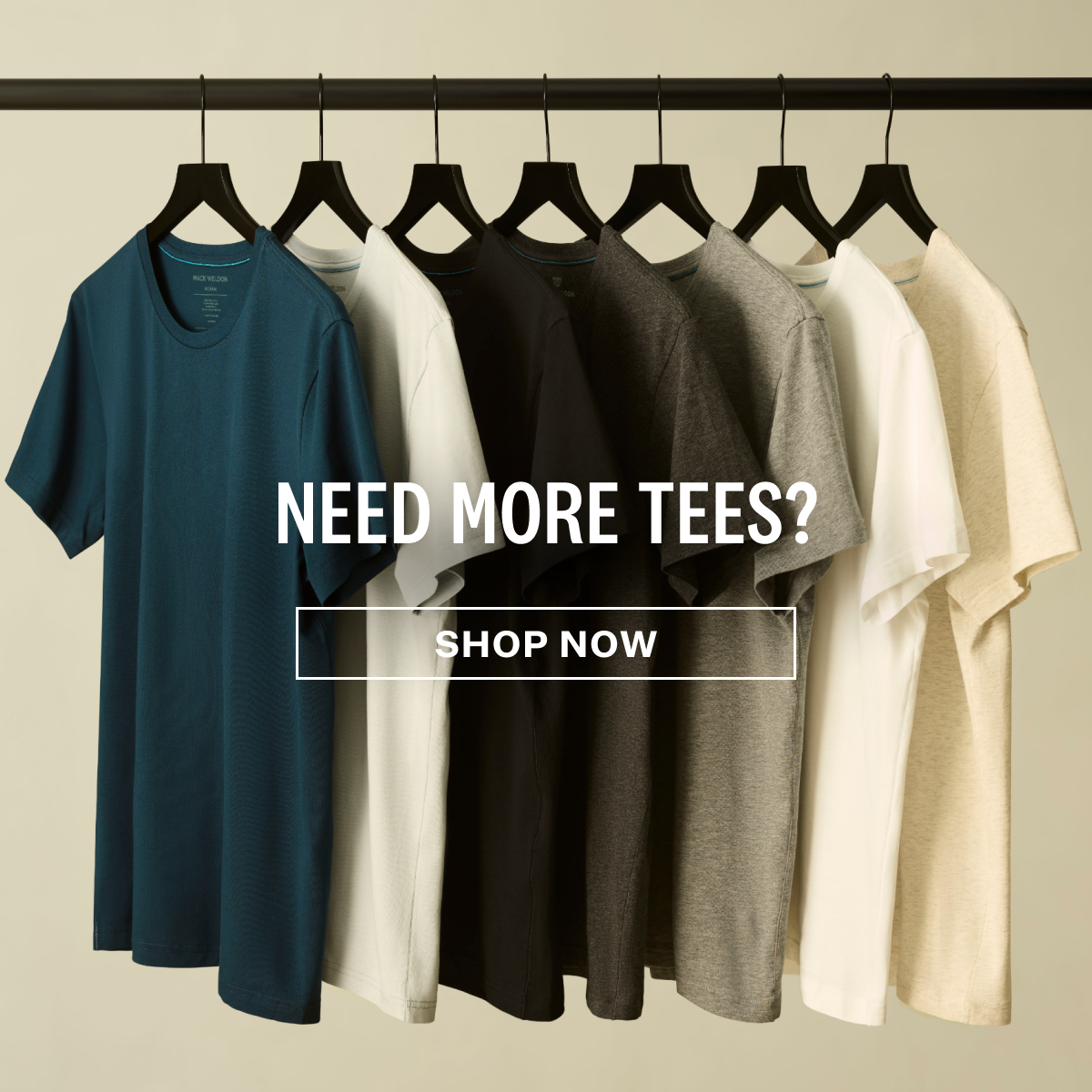 Mack Weldon shirts hanging on black hangers with text Need more tees? Shop now