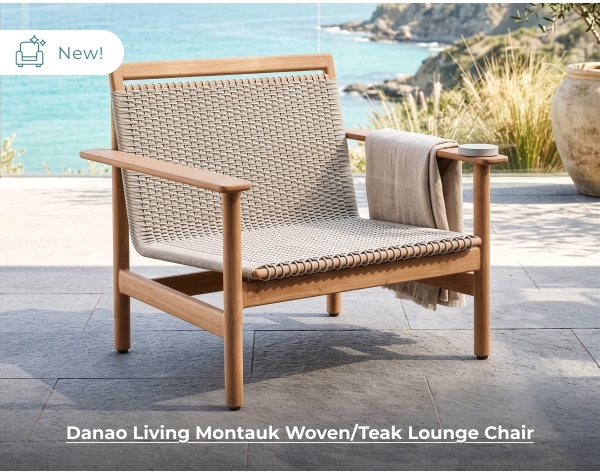 A modern wooden outdoor lounge chair with a beige woven seat and backrest is positioned on a stone patio overlooking a coastal ocean view. Image Text: New! Danao Living Montauk Woven/Teak Lounge Chair