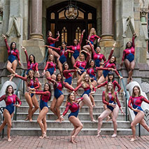 The women's gymnastics team in uniform on the steps of College Hall.