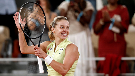 A tennis player holds a racket aloft.