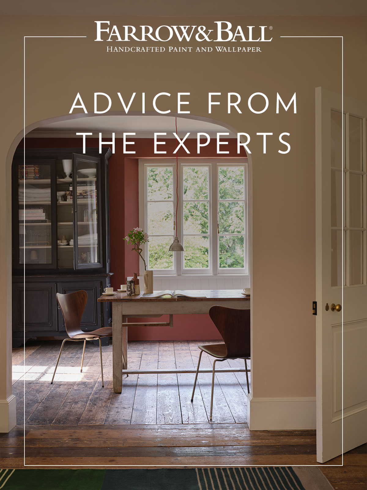 A door opens onto a room with pale dusty pink walls, giving a warm glow to the room. As you move through, the walls become a deeper, rich terracotta, reflecting the warm wooden floorboards and contrasting with the navy blue painted dresser. It makes you want to pull up one of the chairs around the table and linger over a cup of coffee.