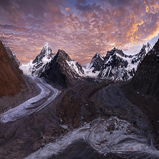 A view of a snowy mountain range at sunset.