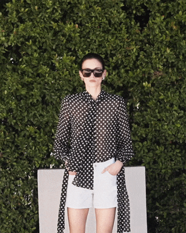 b'The model is wearing The Polka Dot Nouvelle Blouse paired with The Hang Short in white.'