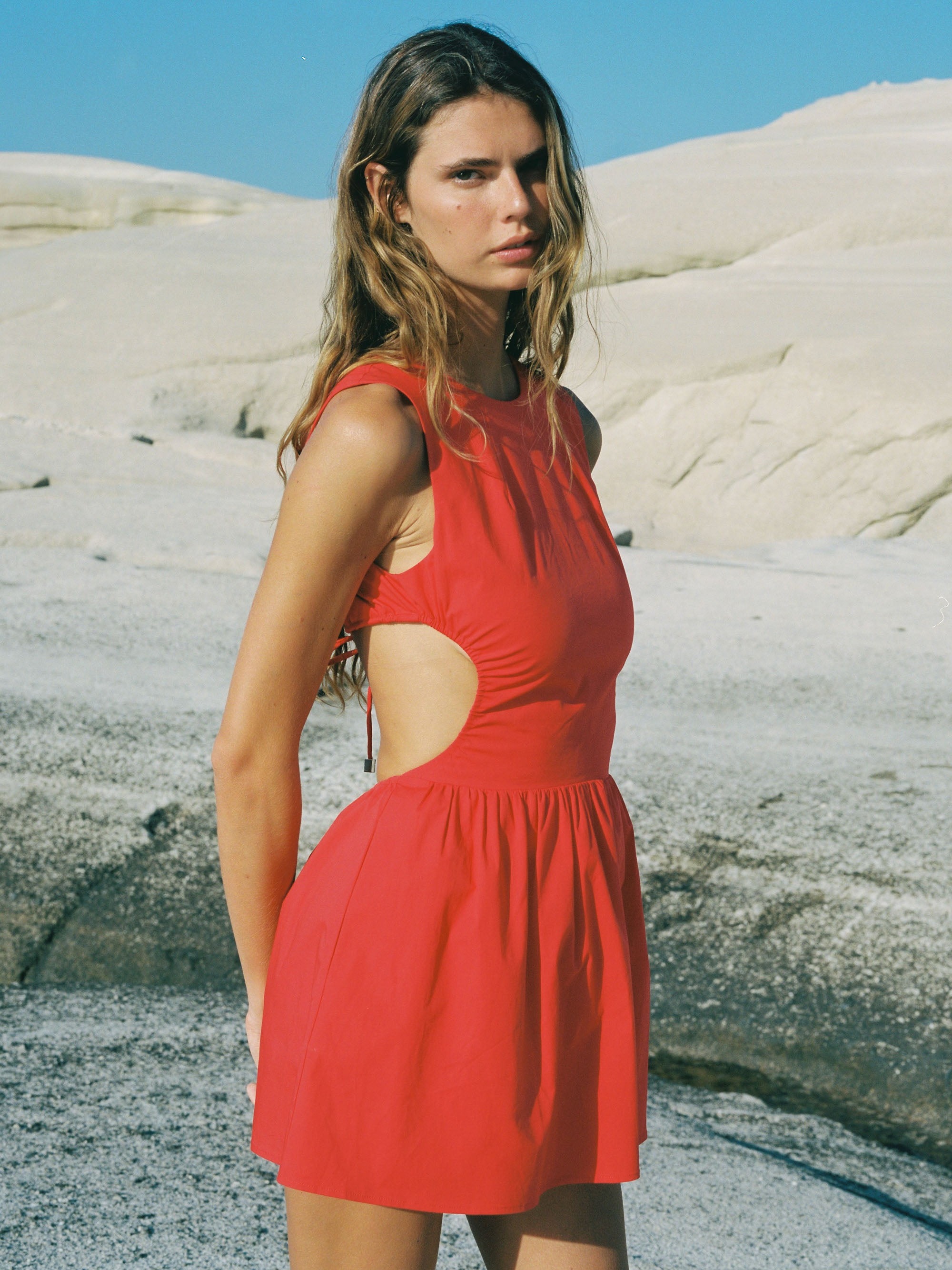 Woman wearing red mini dress with stone background