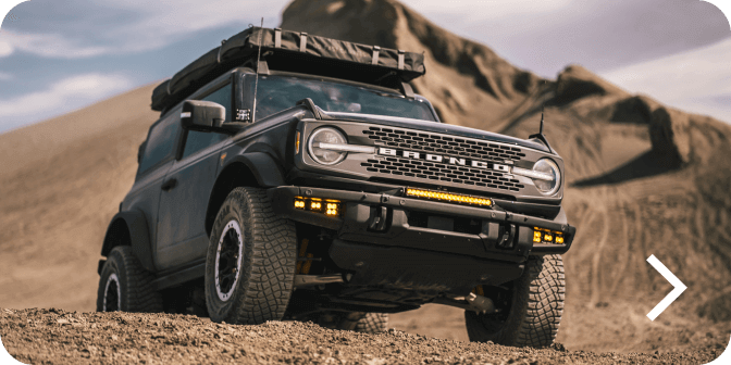 A Bronco&reg; SUV with Sasquatch&reg; Package being driven off‑road in a desert landscape