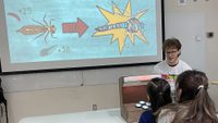 student presents game about dragonfly life cycle in front of classroom