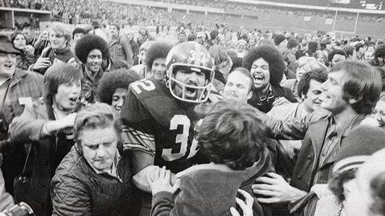 People crowed around a football player in celebration.