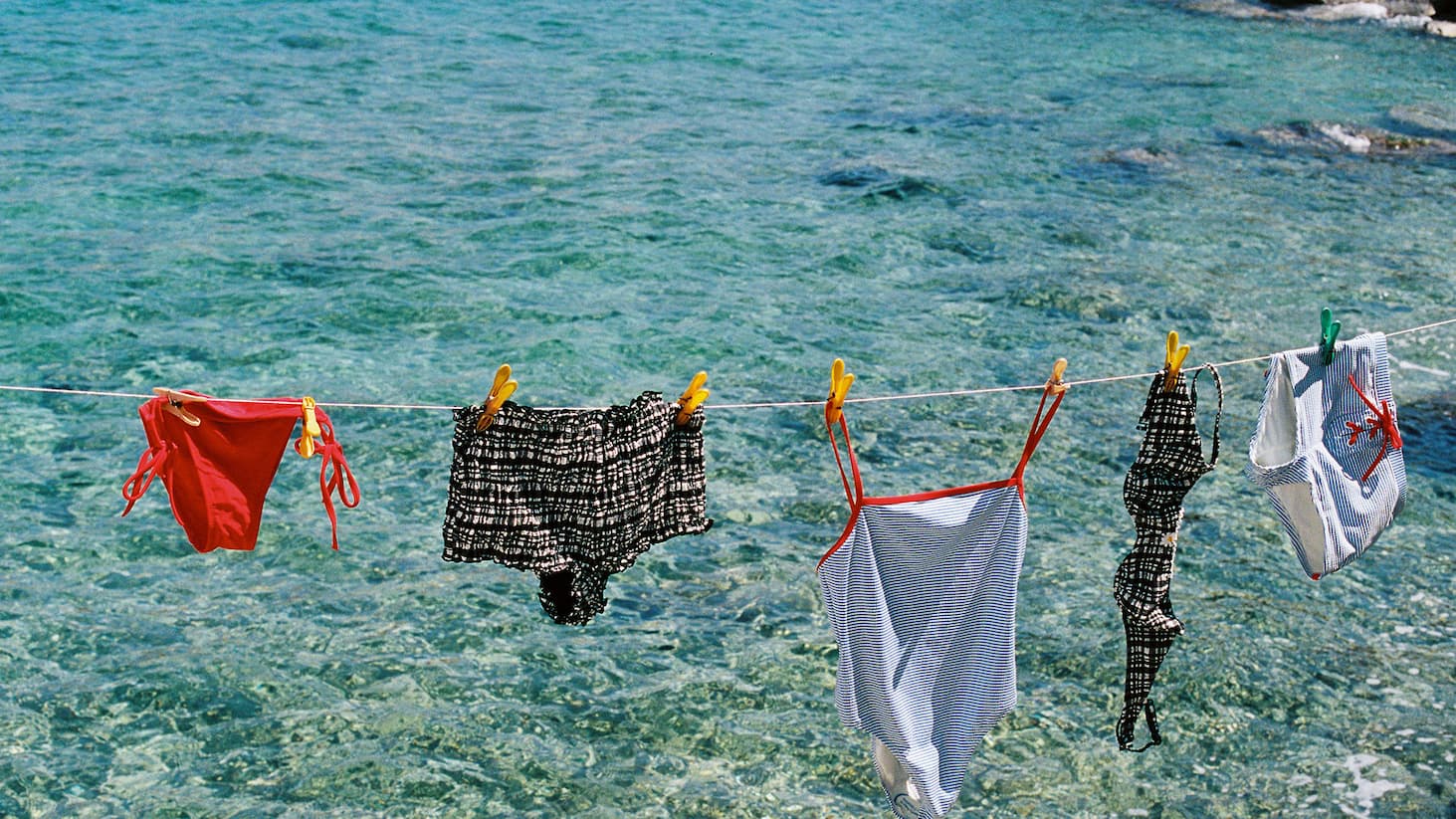 Swimwear hanging on a clothesline by the water