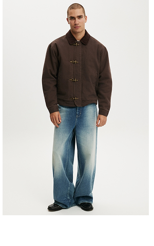 Man model wearing brown suede jacket with toggle buttons and blue jeans
