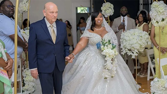 A man walks a woman down the aisle at her wedding.