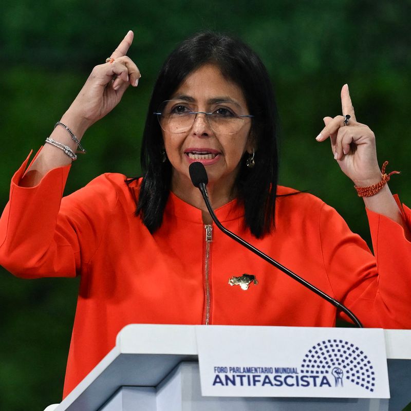 Figure stands at podium making hand gesture