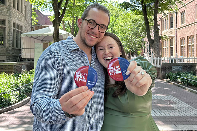 A couple holding buttons that read "I met my partner at Penn."