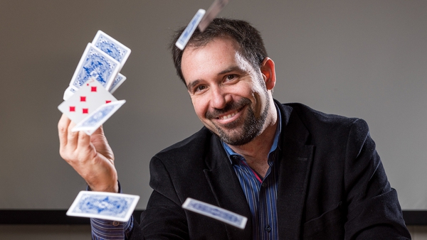 Matt Baker smiling with playing cards flying around his head