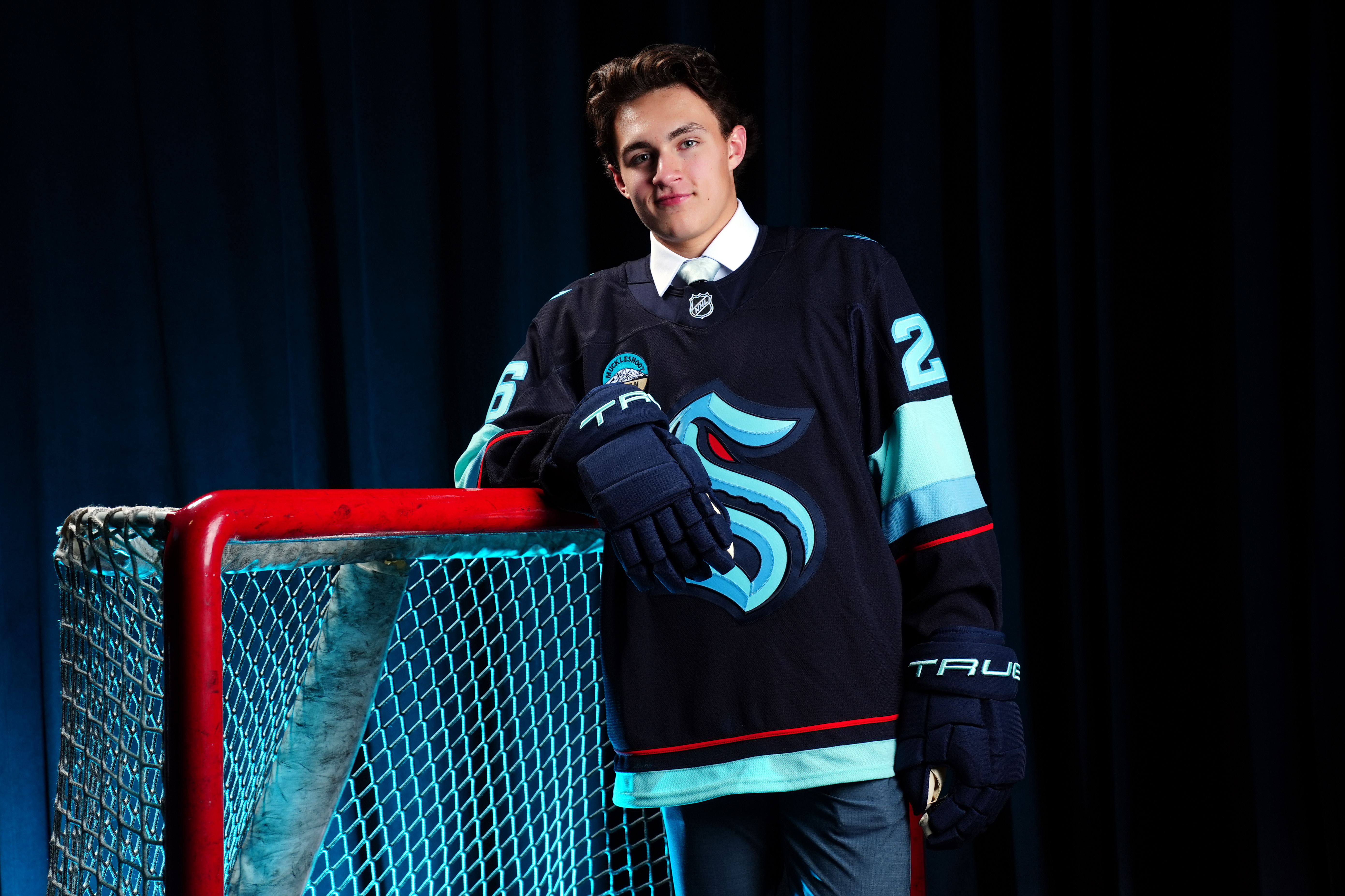 Chase Reid posing near a goal post with Kraken jersey on