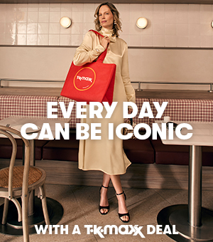 A woman elegantly dressed in a cream satin dress holding a red TK Maxx shopping bag.