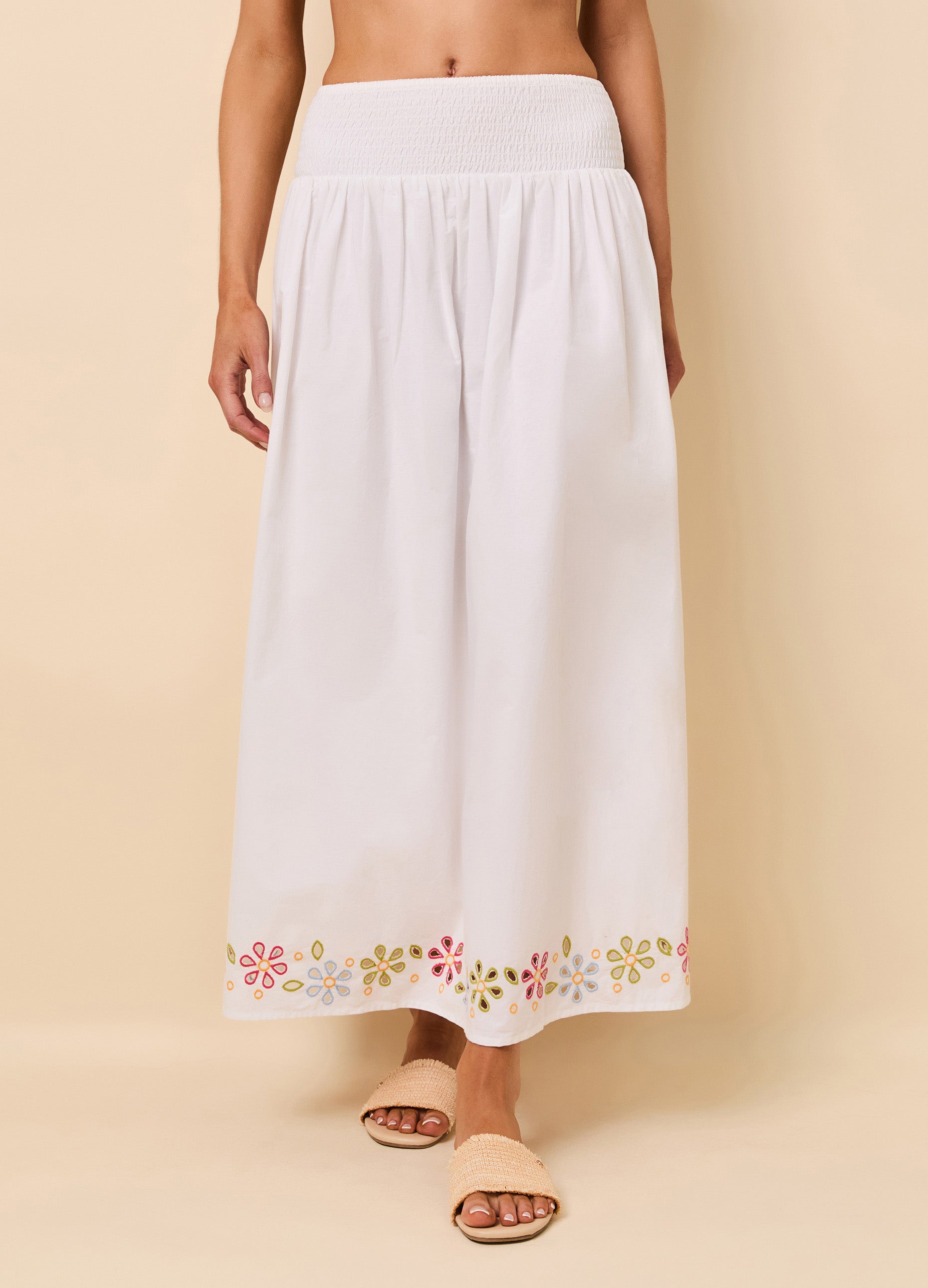 close up of woman in white maxi skirt with colorful floral eyelet detail at the bottom