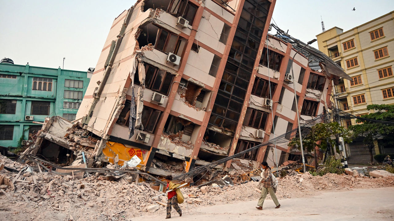 Children walk past a collapsed building in Mandalay