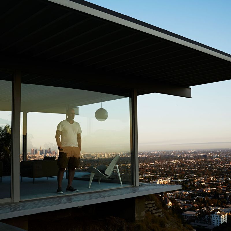 Man looking out the window in a modern house overlooking the city.