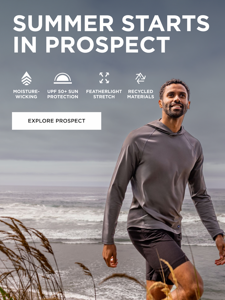 Man walking along the ocean wearing grey Prospect pullover and shorts | EXPLORE PROSPECT