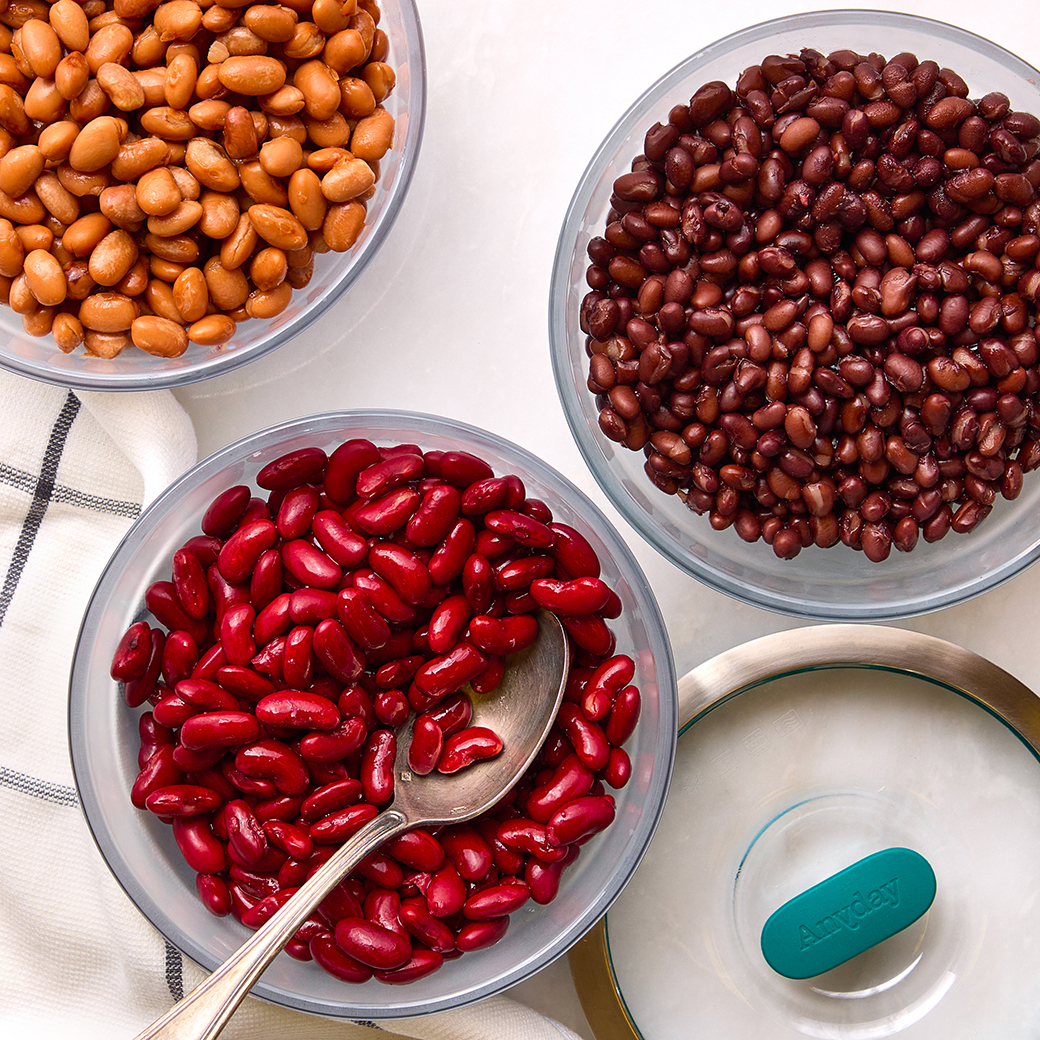 Three Anyday glass dishes filled with cooked pinto beans, black beans, and red kidney beans, shown with a teal silicone-handled glass lid. Ideal for cooking, storing, and reheating beans in the microwave.