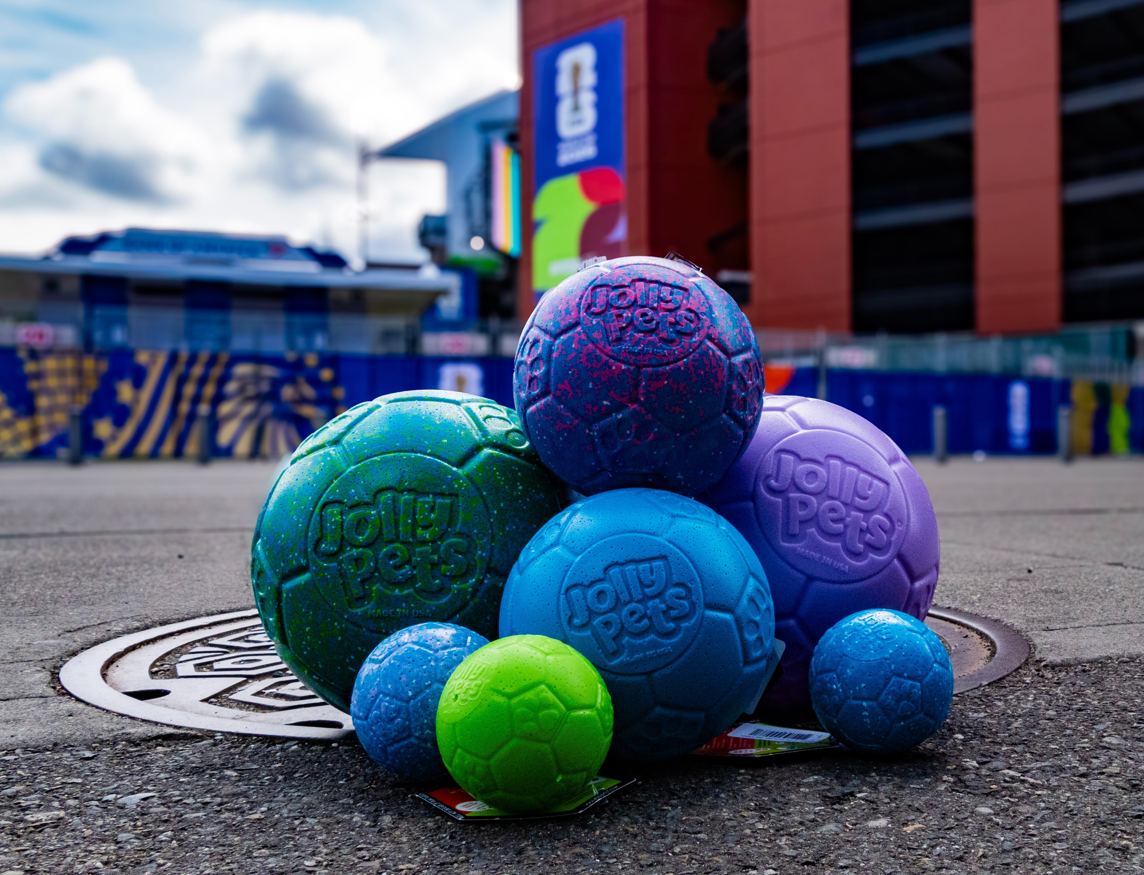 Image of a selection of Jolly Pets Soccer Balls in both sizes 8'' & 6'' sizes in front of Lumen Field in Seattle. 