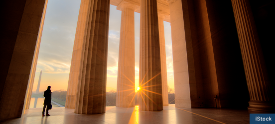 The silhouette of a person standing by columns at the entrance of the Lincoln Memorial
