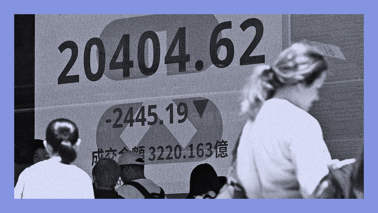 People walk past an electronic display board showing the Hang Seng Index