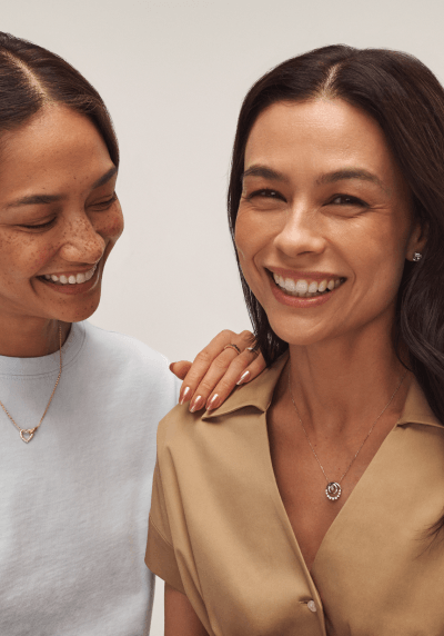 Two smiling women wearing variety of fine jewelry.
