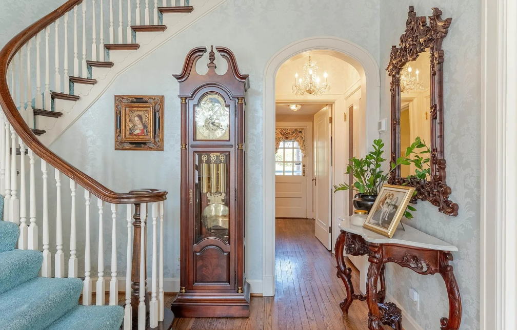 A grandfather clock next to a winding staircase