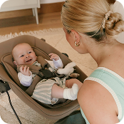 Baby in bouncer smiling at Mum