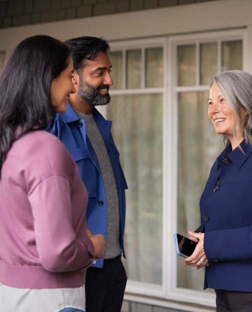 A couple talking to a real estate agent outside of a home