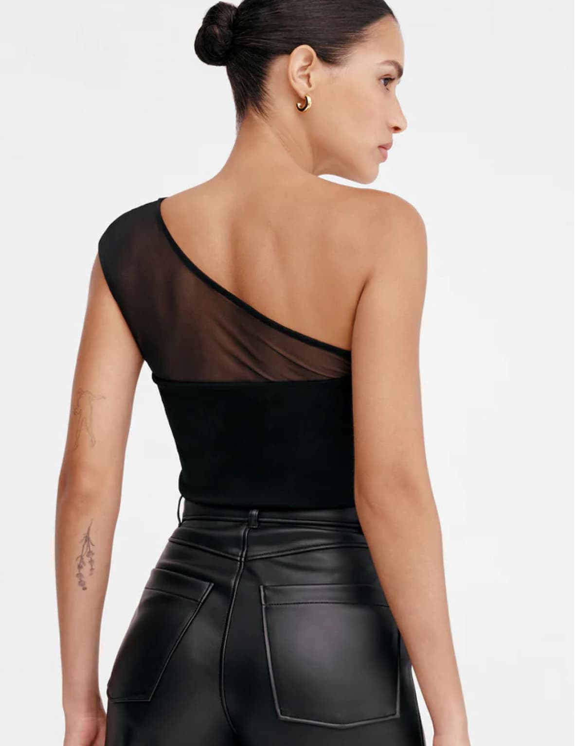 Back view of Astrid in The Parker Top showing a sheer mesh back panel, paired with black leather pants.