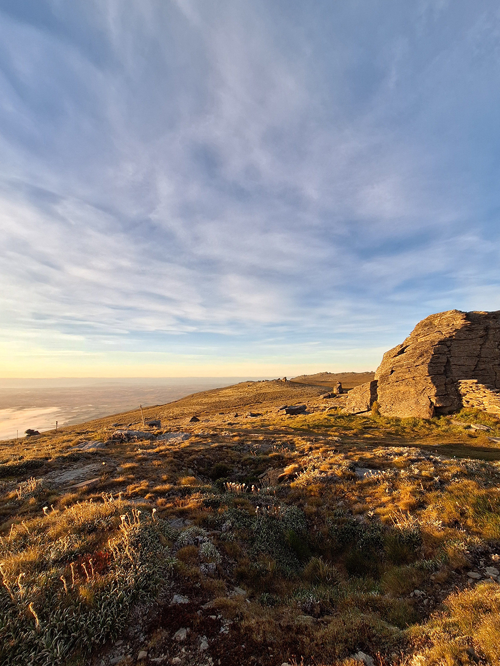 A view of a rocky outcrop on top of a mountain at sunset.