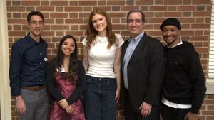 five people pose in front of brick wall