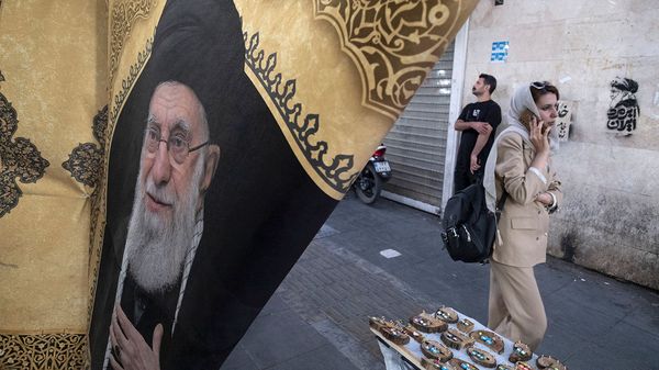 An Iranian woman walks past a portrait of Iran's late Supreme Leader Ayatollah Ali Khamenei in downtown Tehran