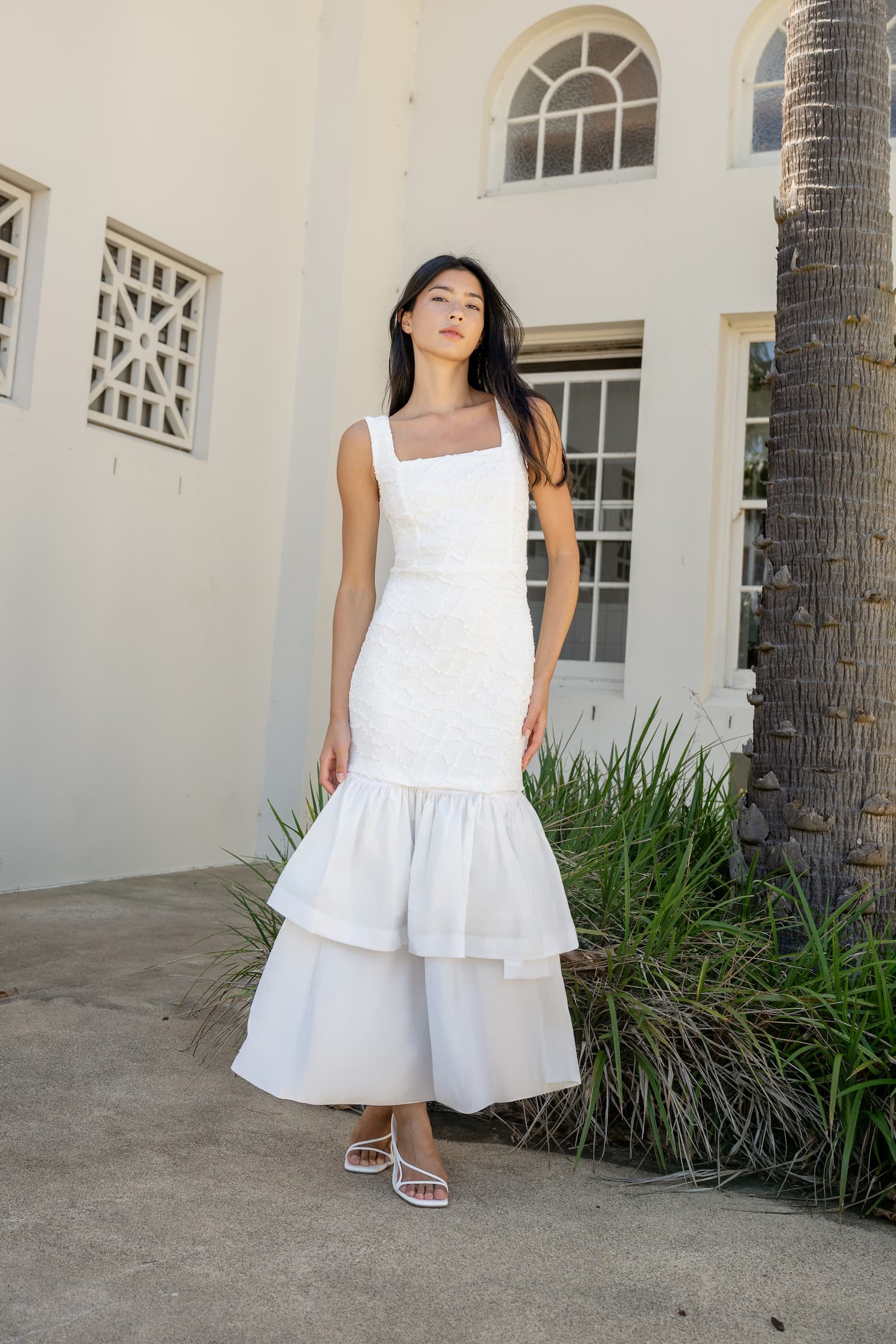 an image of a woman in a dress standing by a pillar