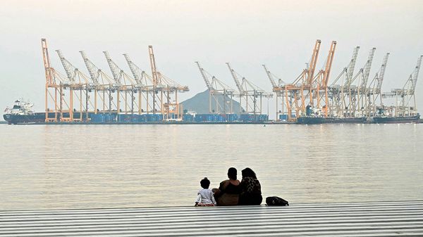 A family sits against the backdrop of a dockyard in Khor Fakkan in the Gulf emirate of Sharjah