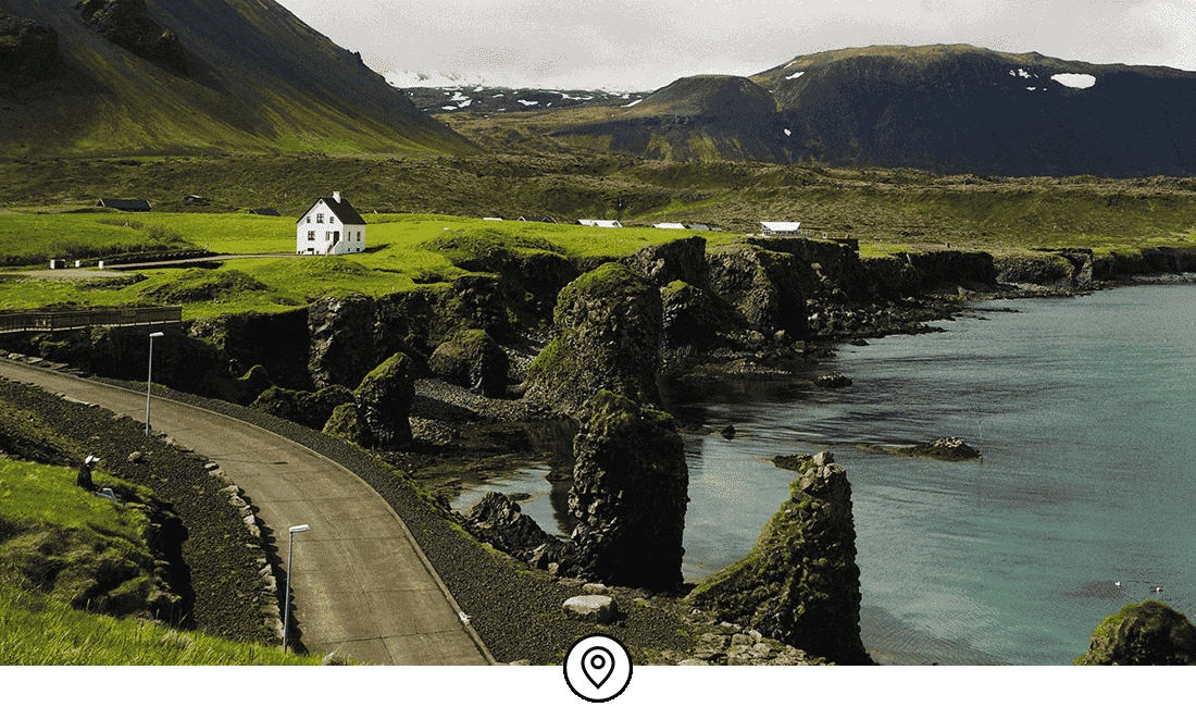 Image Description: A seaside road in Iceland set against green rolling hills
